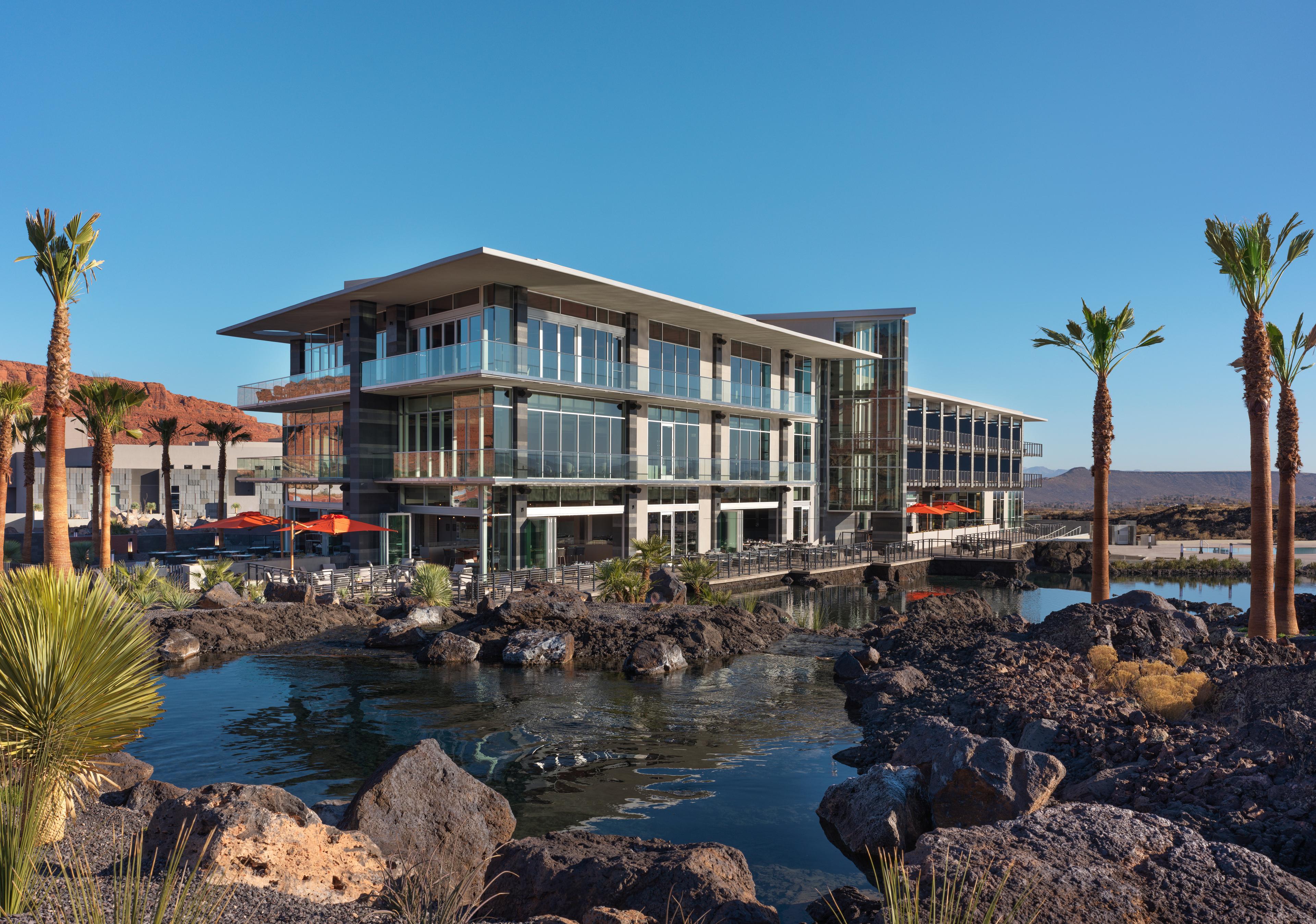 The glass Black Desert Resort surrounded by a rocky lake and palm trees