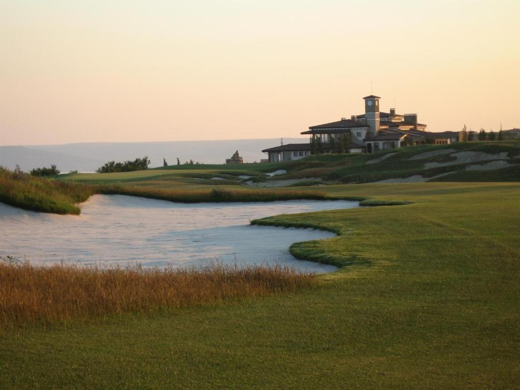 A large sand bunker placed on a well-maintained fairway leading towards the resort building