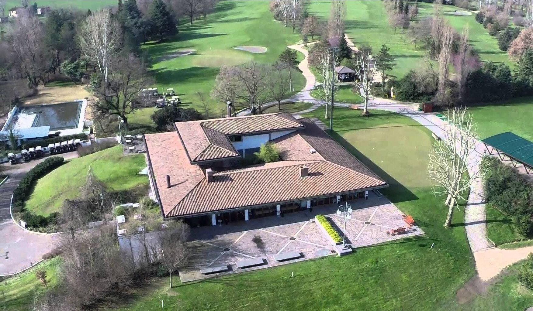 An aerial view of a golf clubhouse with surrounding fairways and practice areas.