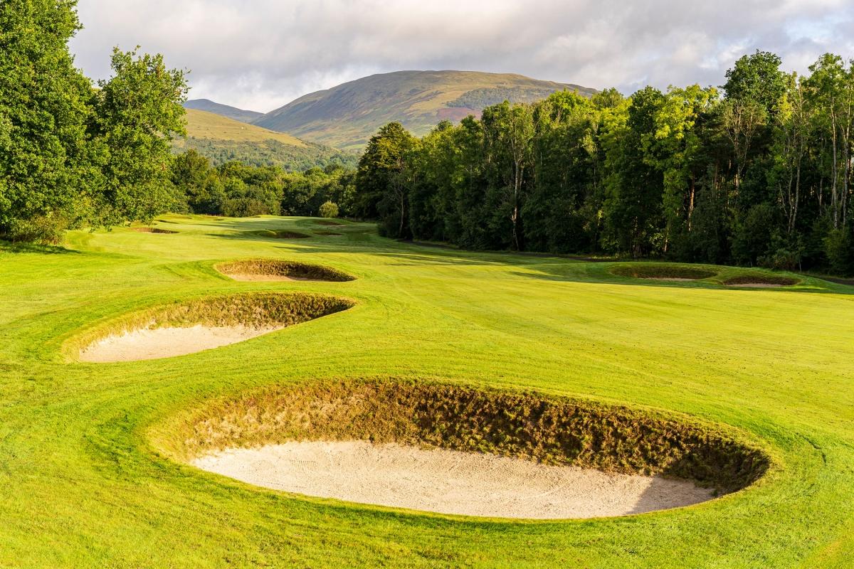 Deep sand bunkers strategically placed around the green with mountain views in the distance