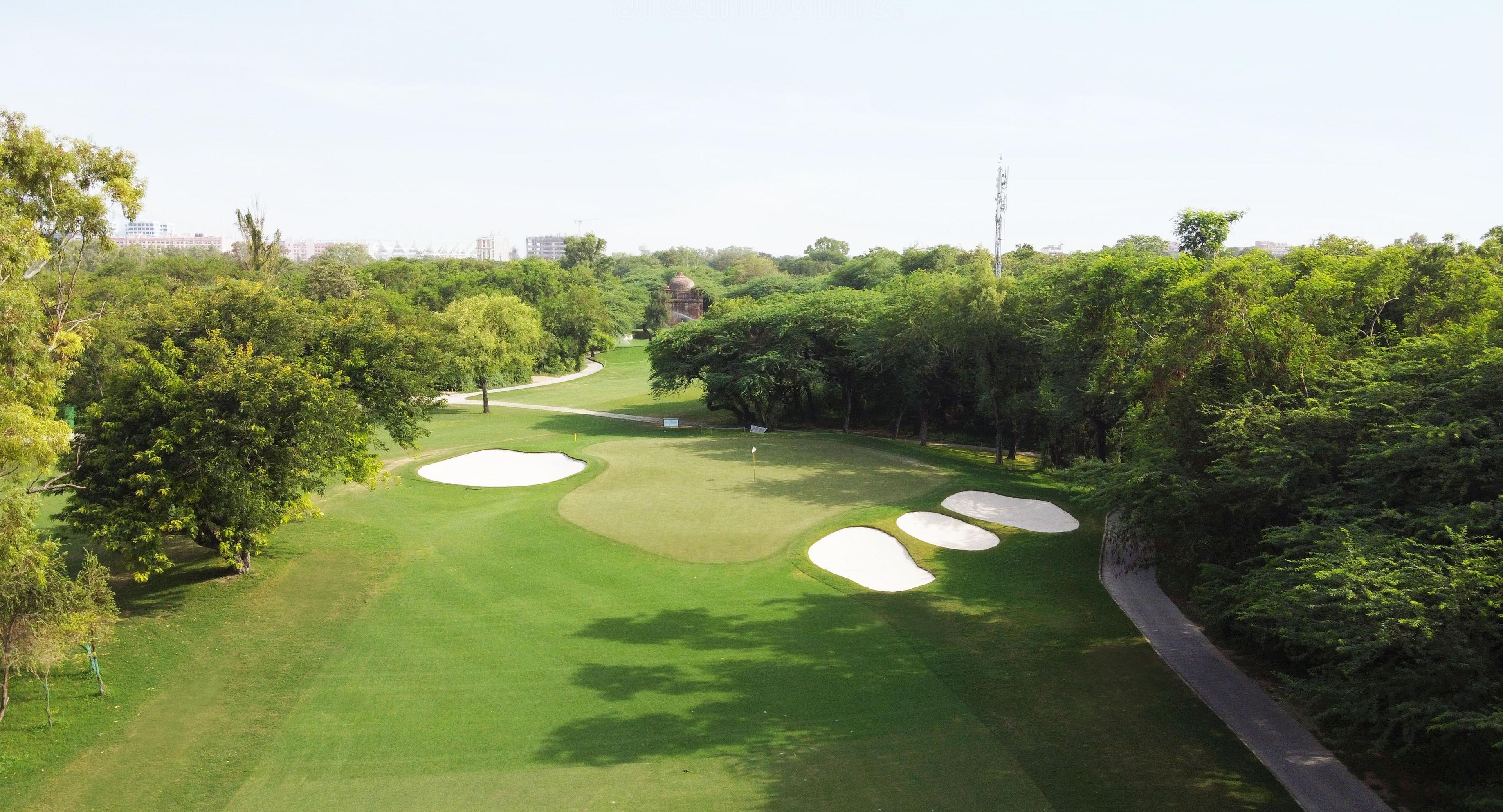 A smooth green lined with sand bunkers with surrounding dense greenery.