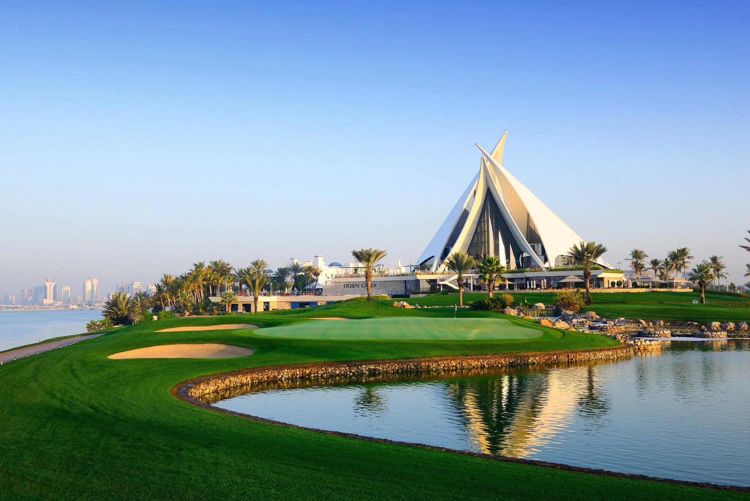 The Dubai Creek's modern clubhouse overlooking a smooth green surrounded by sand bunkers on the course