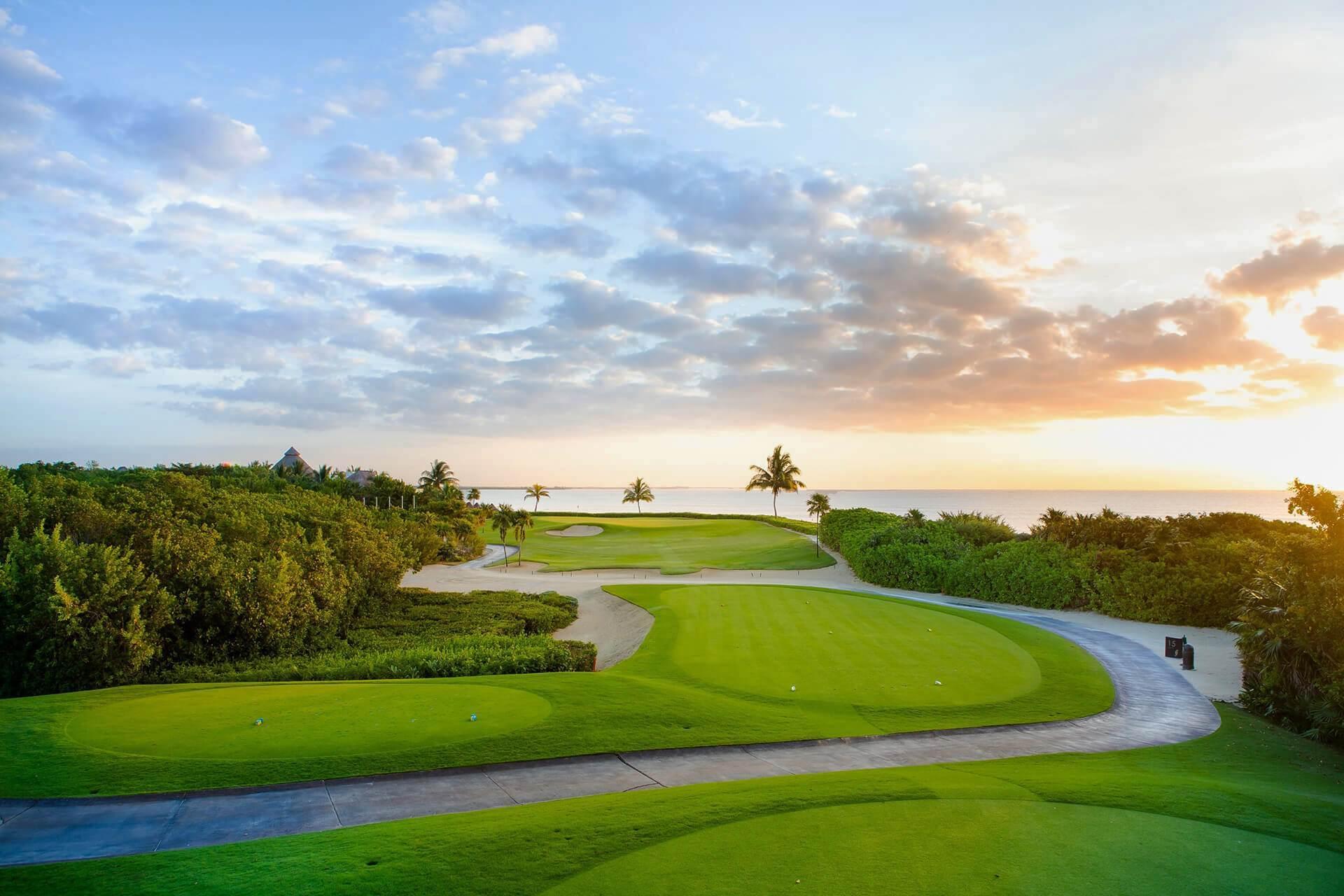 Sun setting over a manicured green with sea views