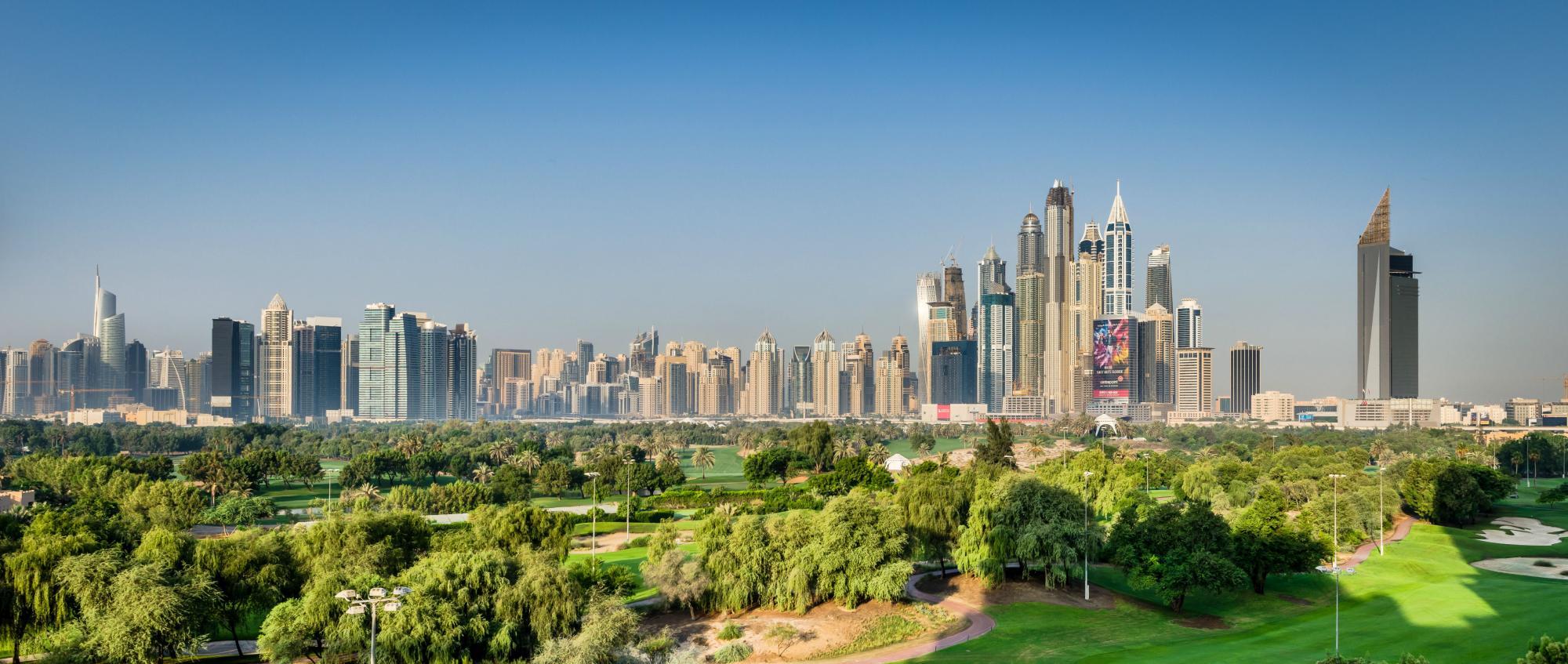 A panoramic view of a lush golf course set against Dubai's impressive skyline.