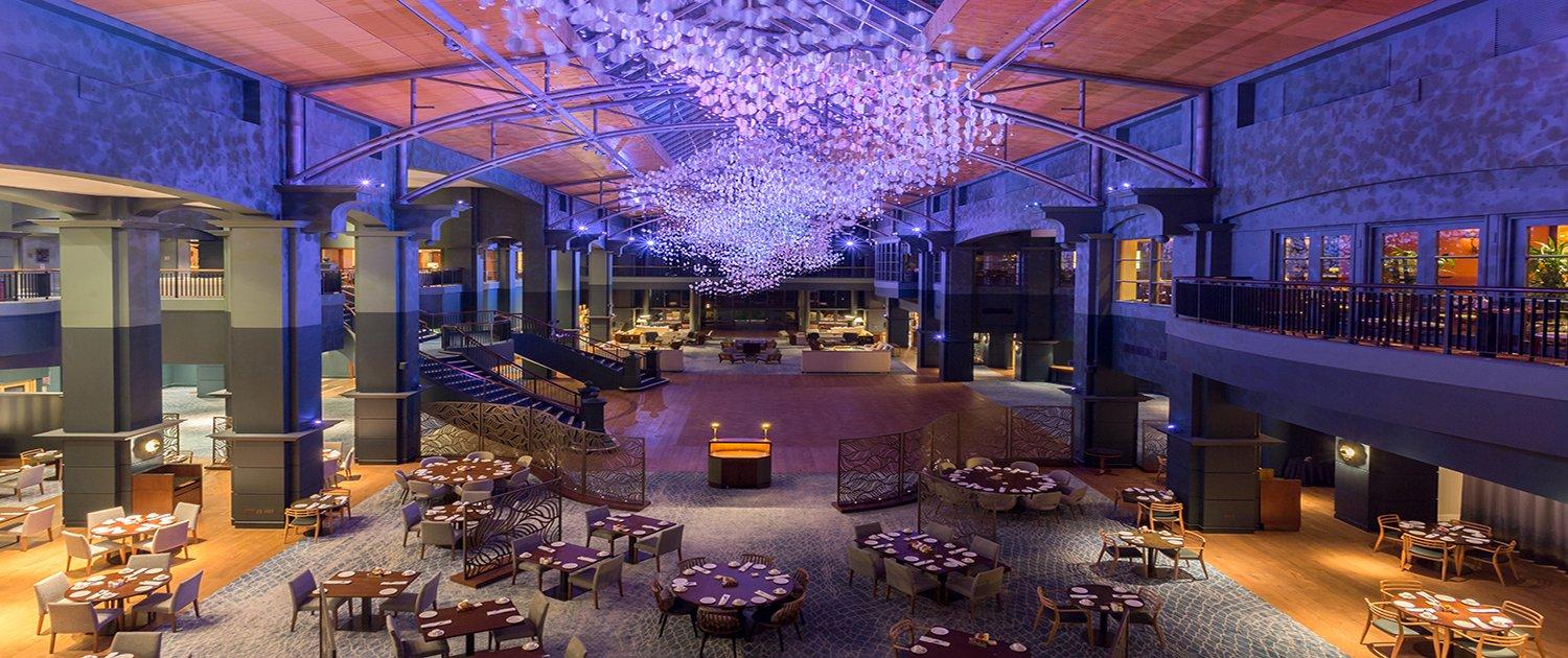 Modern restaurant with dramatic purple lighting and artistic ceiling design.