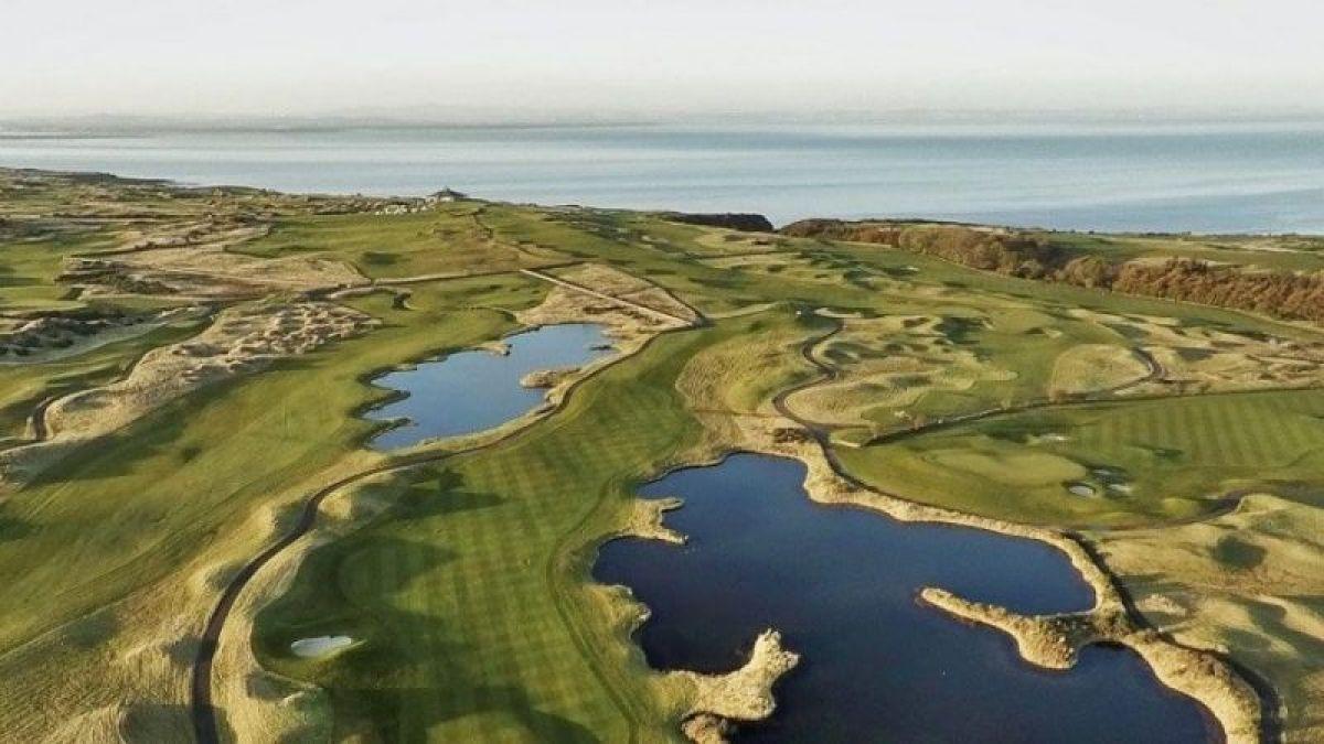 A spectacular aerial view of a coastal golf course with water hazards and sea views.