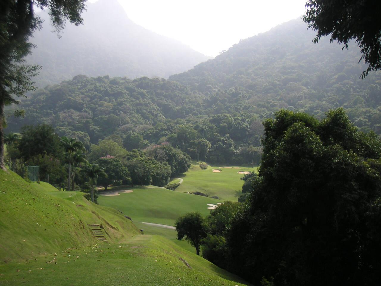 A hilly golf course surrounded by dense, tropical forest