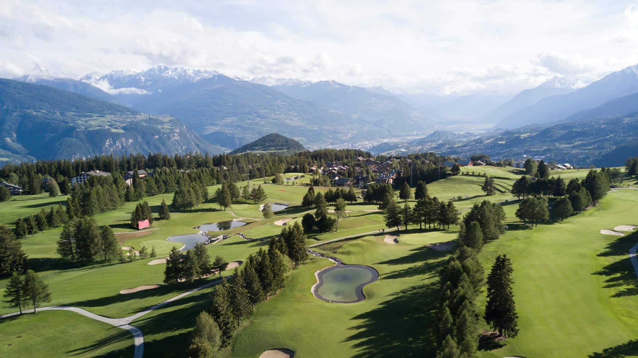 Overhead view of the Golf Club de Crans Sur Sierre with ice top mountains in the distance