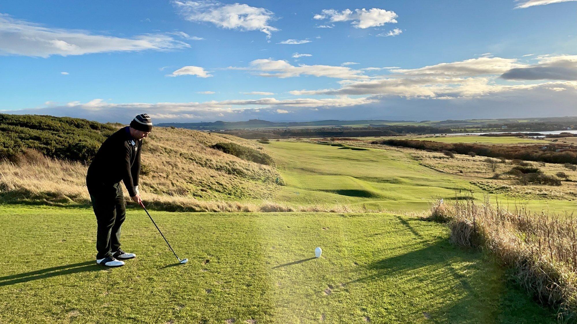 A golfer prepares for a perfect swing with panoramic views of the lush landscape.