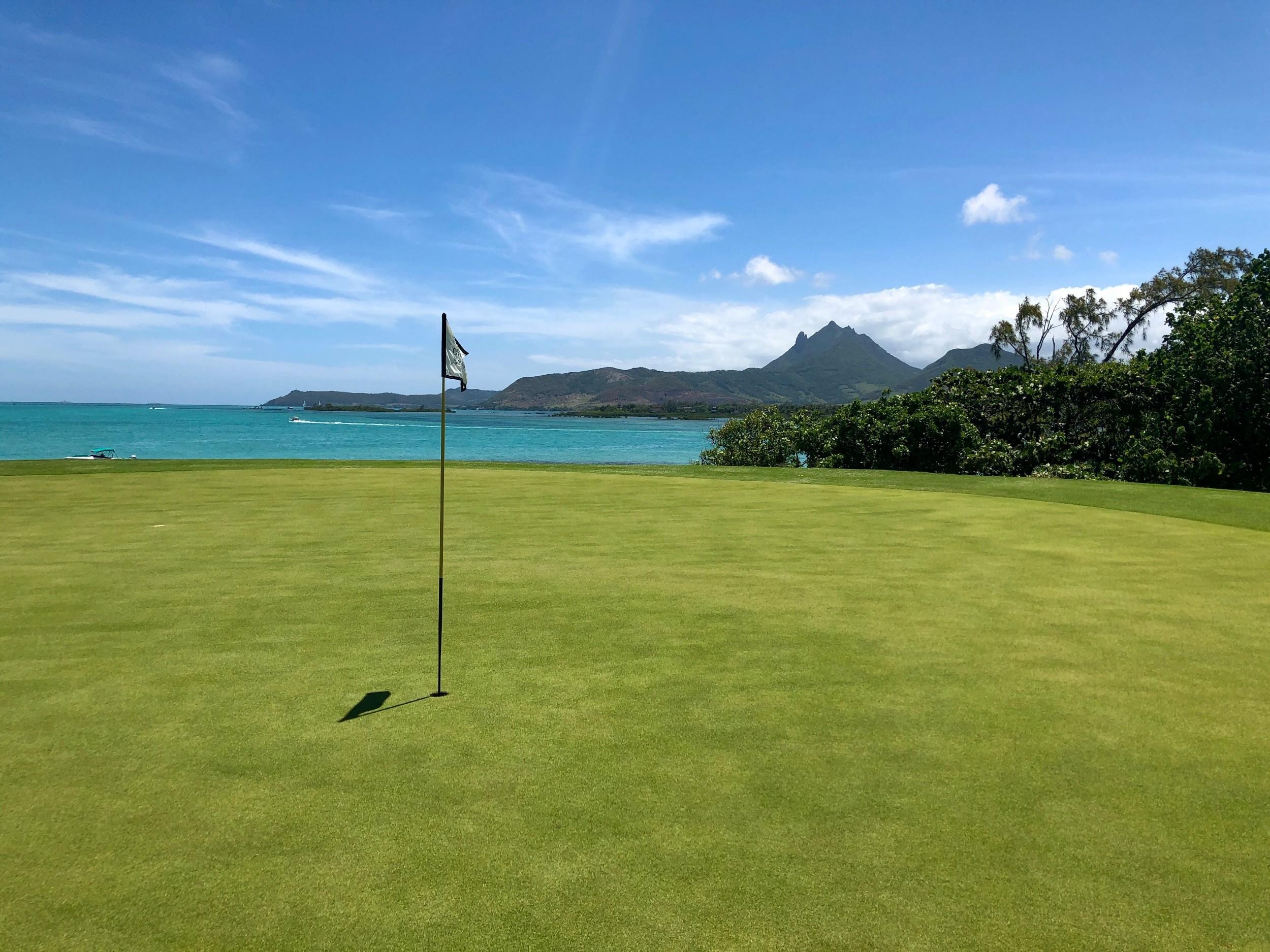 A smooth green looking out to coastal views and a mountain in the distance