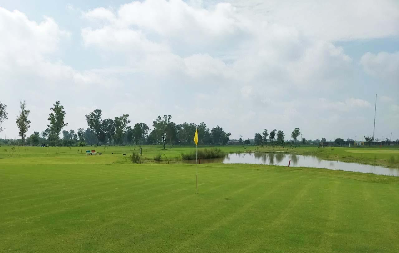 A smooth green with a yellow flagstick next to a water hazard at the Jaypee Greens Golf Resort