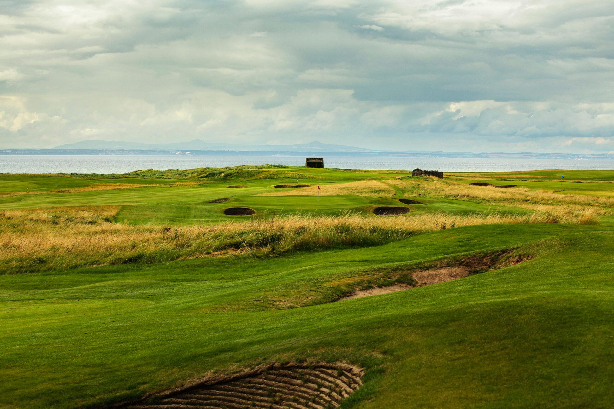 Rolling fairways lined with deep bunkers leading to a green by the sea.