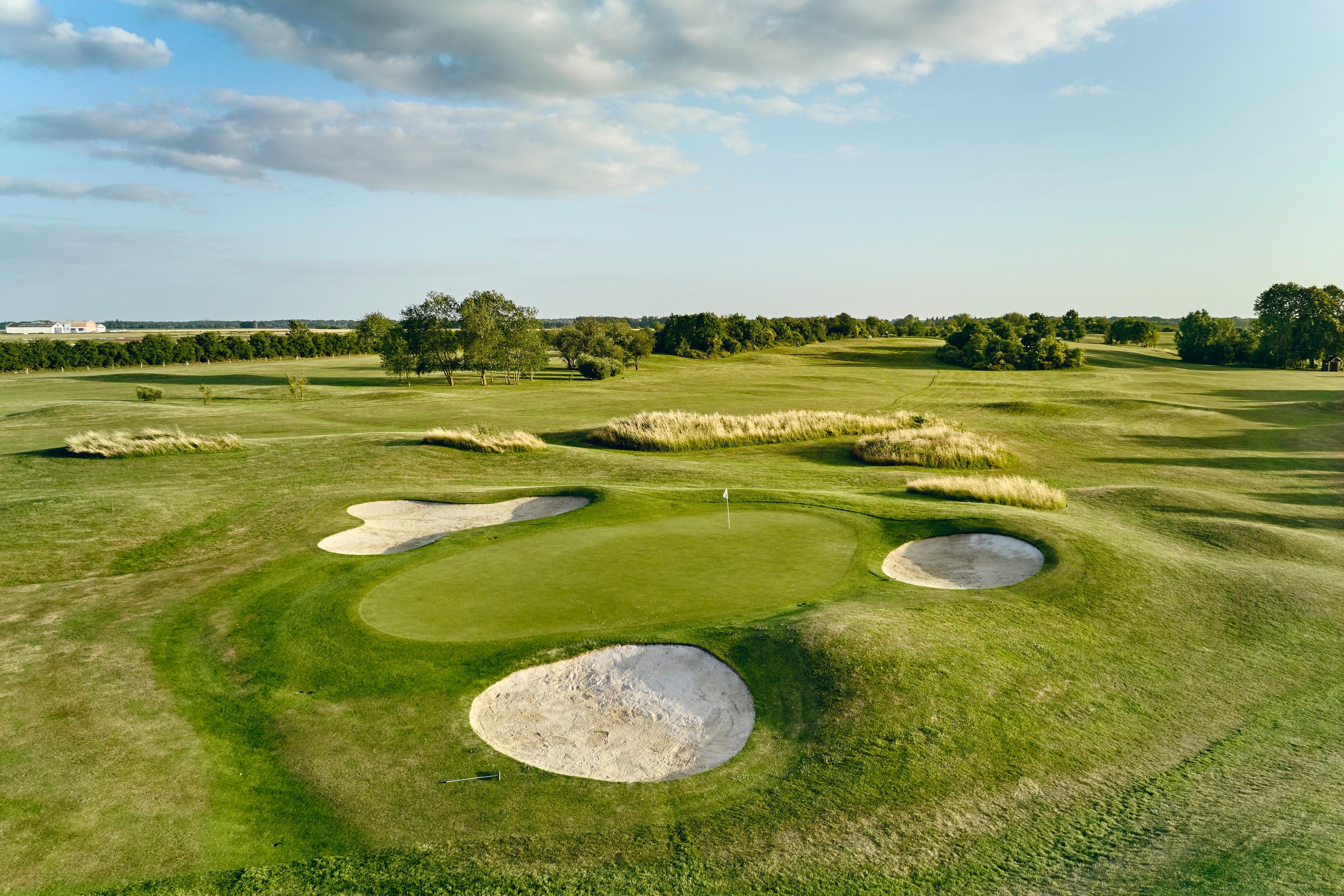 Green surrounded by three bunkers, wide open fairways behind