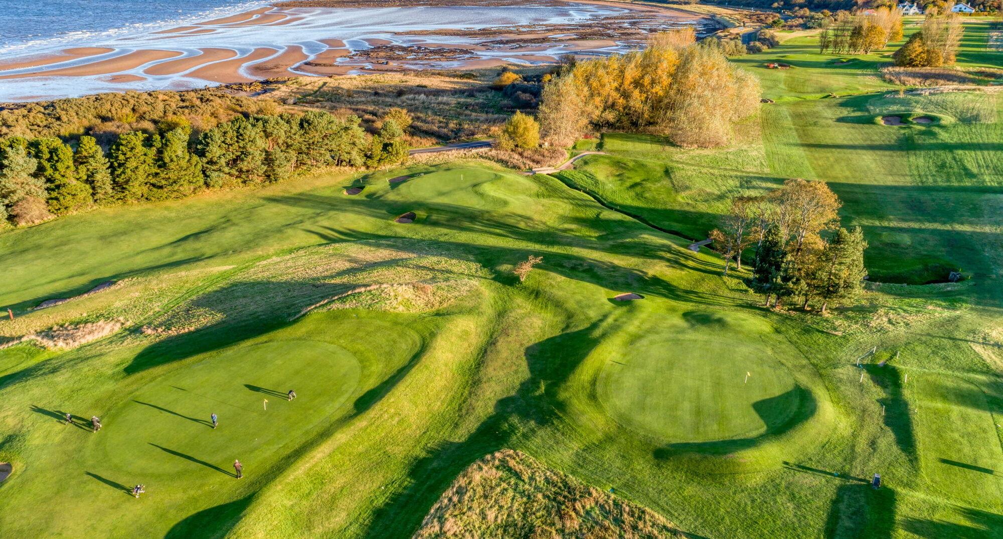 Overhead shot of golfers enjoying their round on the green with costal views