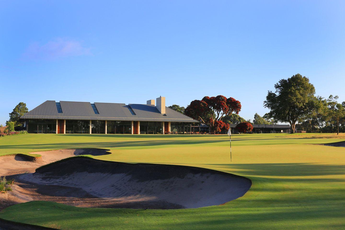 The Metropolitan Golf Clubhouse overlooking a smooth green under clear blue skies