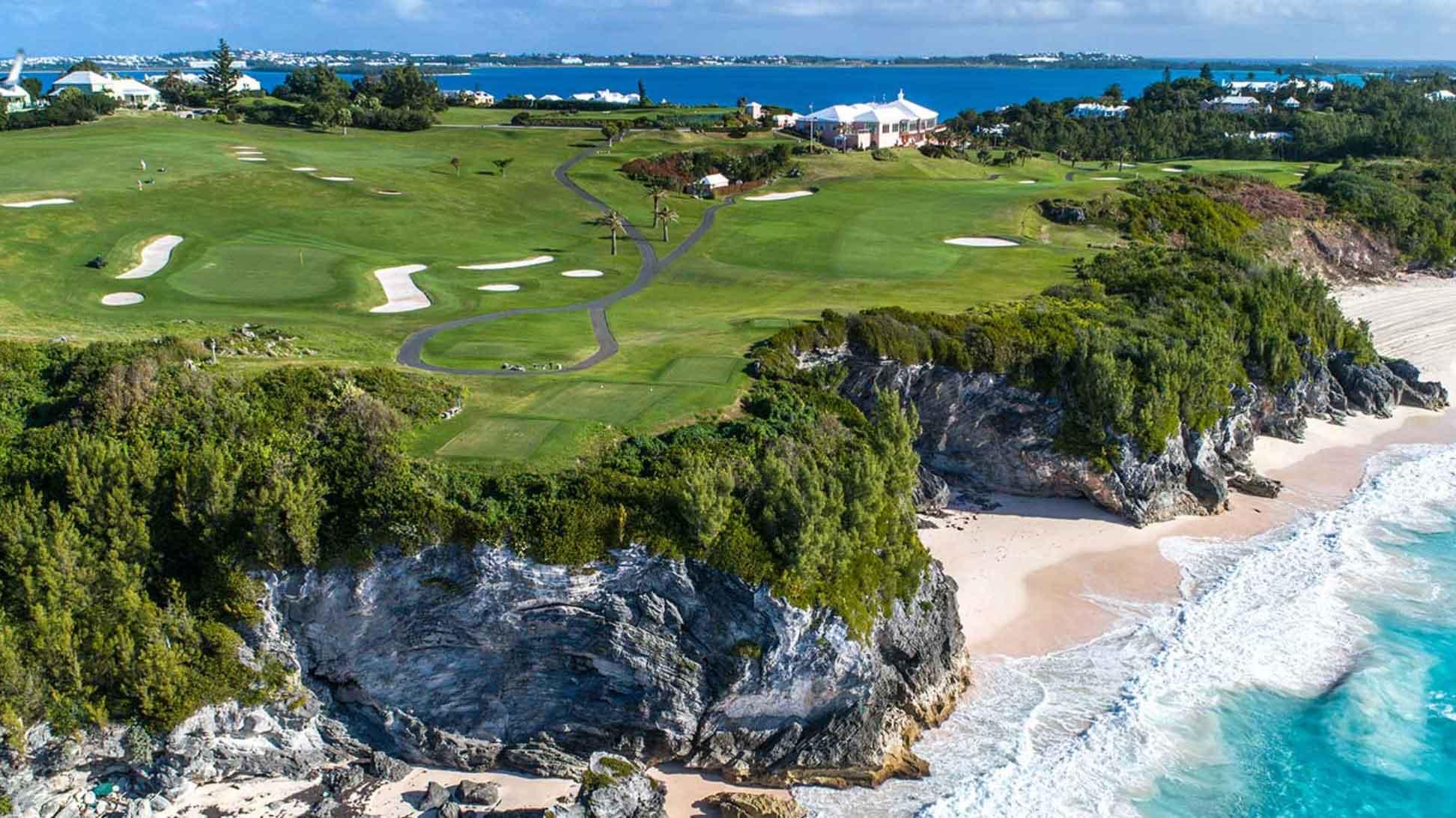 A scenic golf course sits atop dramatic seaside cliffs, with sandy beaches and turquoise waters below.