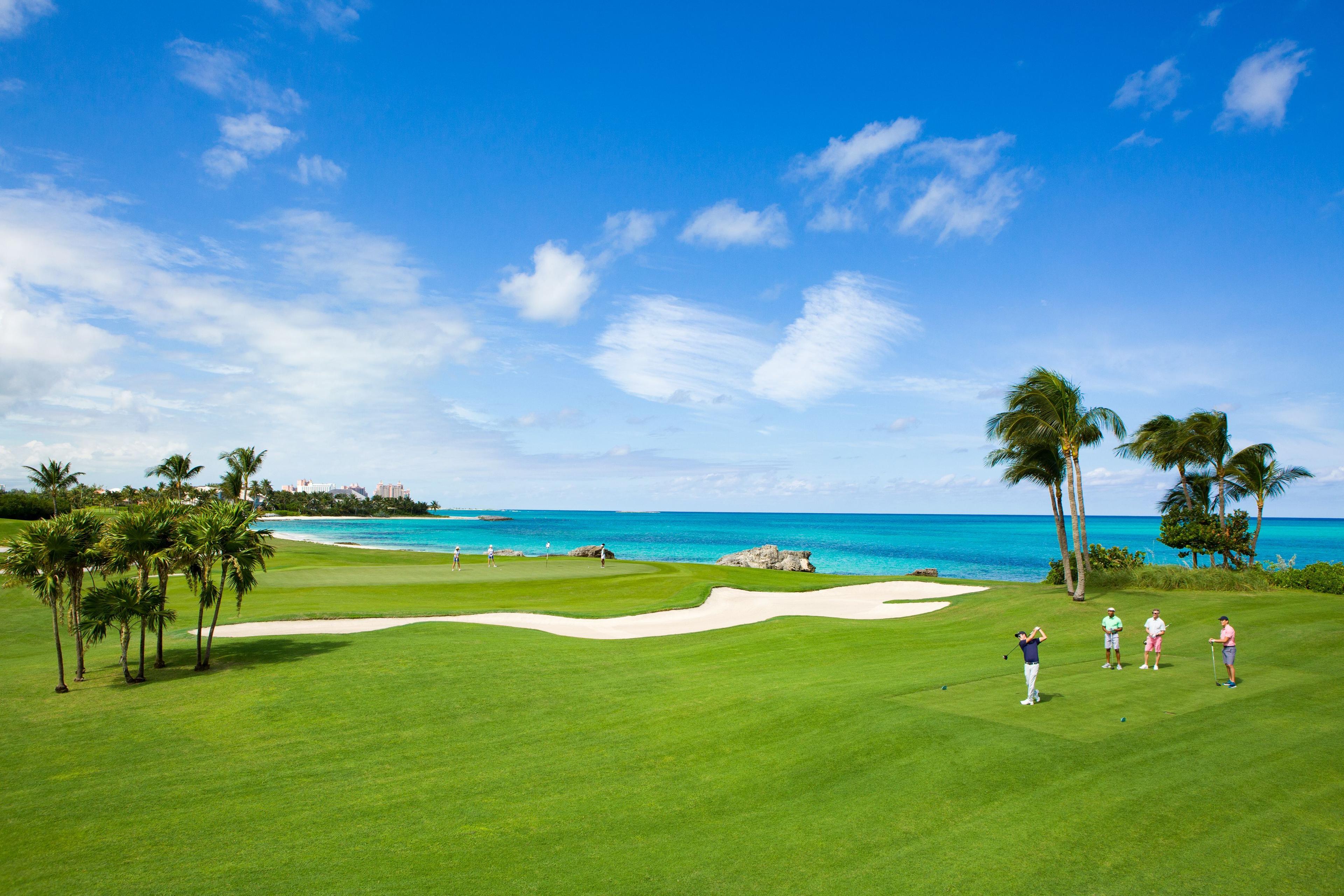 A manicured green and a tee box separated by a large sand bunker