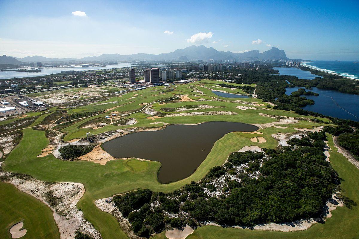 A stunning aerial perspective of a golf course with lakes, greenery, and nearby coastline