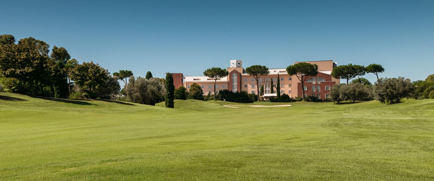 A golf course view leading up to a grand building in the background.