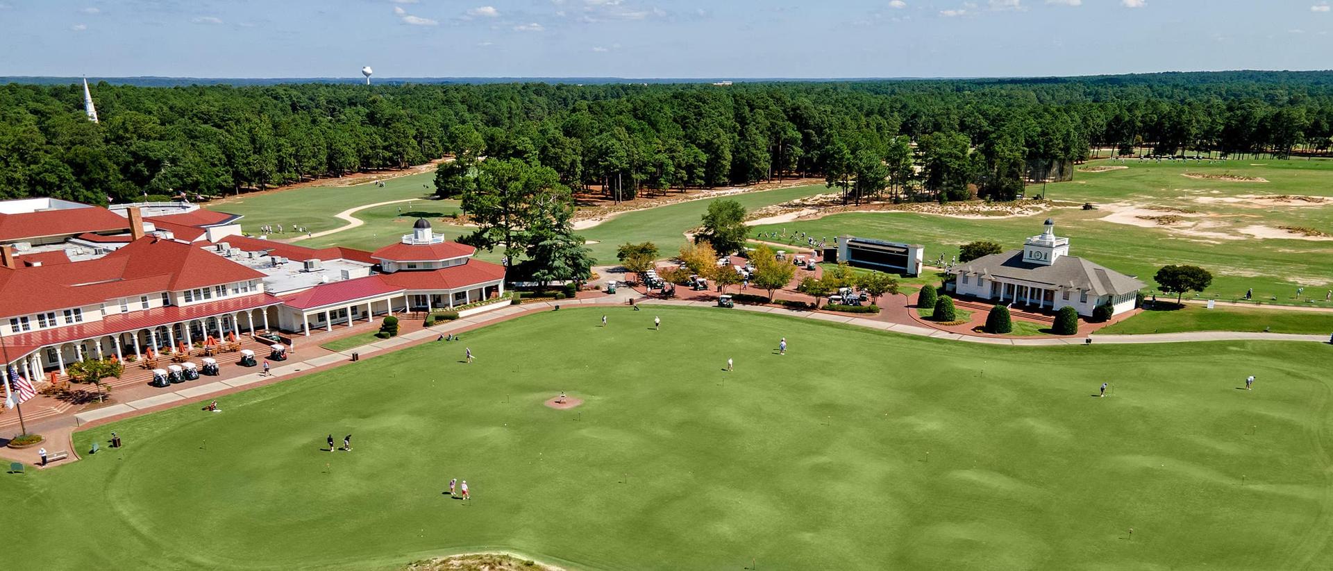 Birdseye view of golfers getting their practice putts in outside of the clubhouse before starting their round