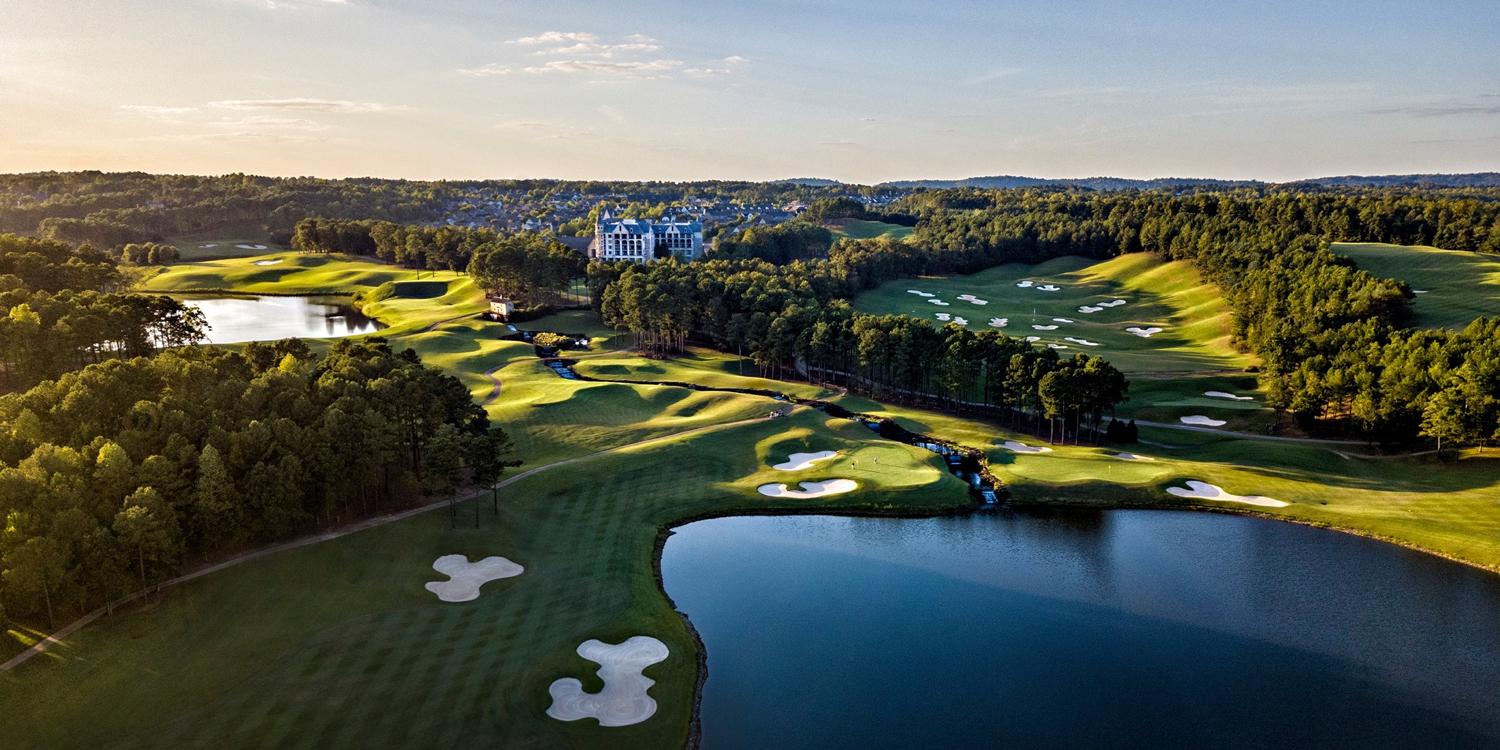 Birdseye view of the course littered with sand bunkers as golfers enjoy their round on a smooth green