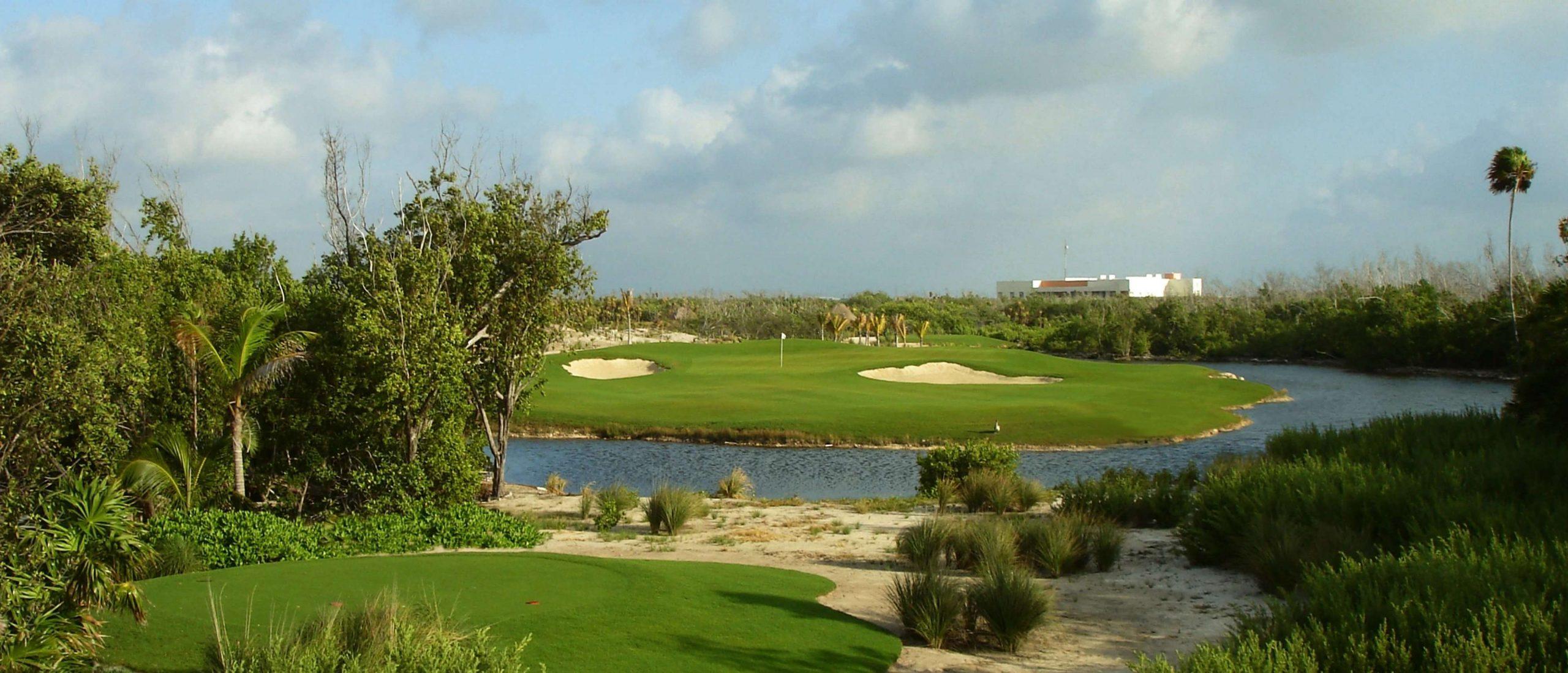 Panoramic view of a smooth green nestled with sand bunkers surrounded by a water hazard