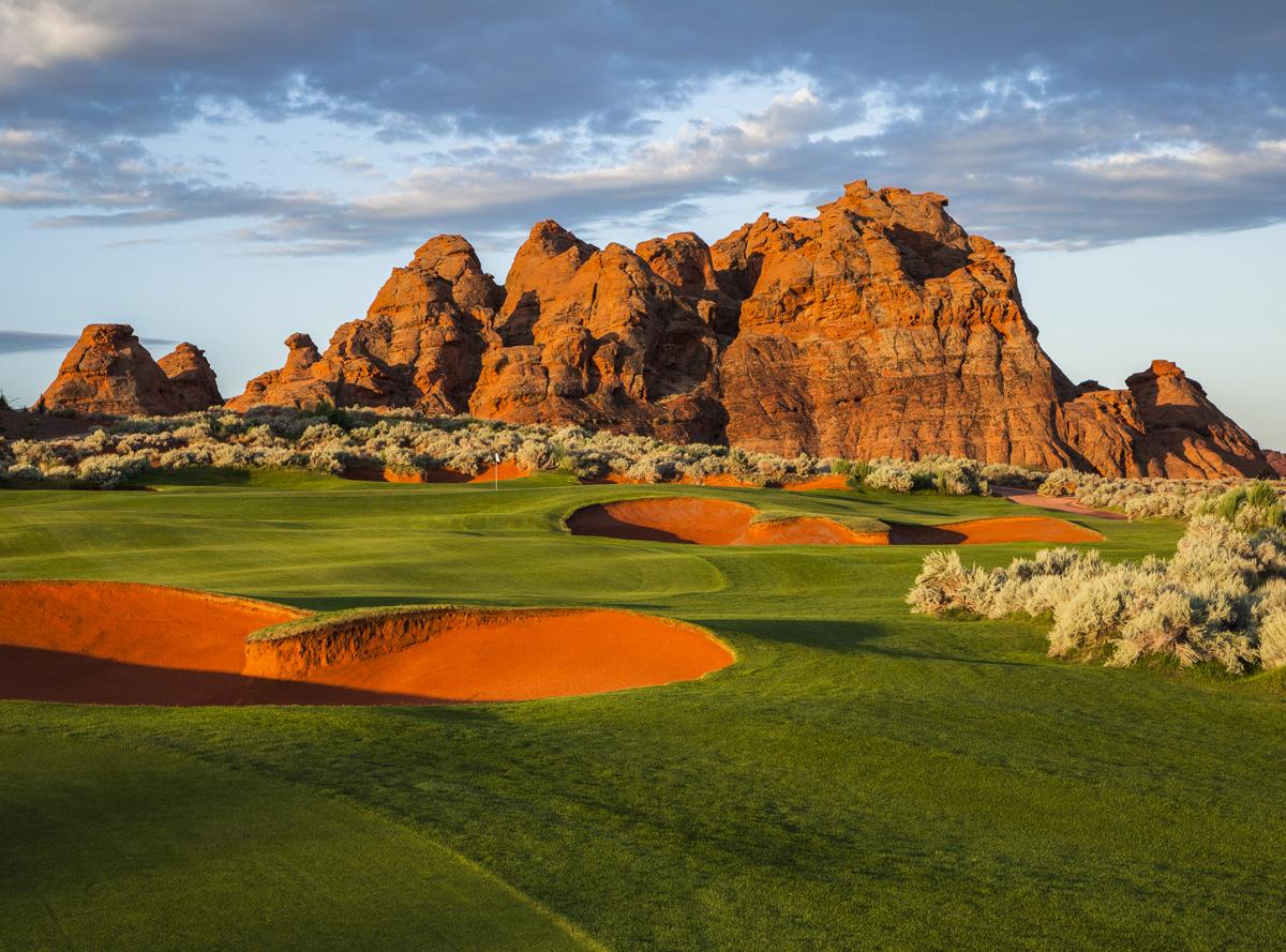 Sand traps contrast with the rugged red rock formations in the background.