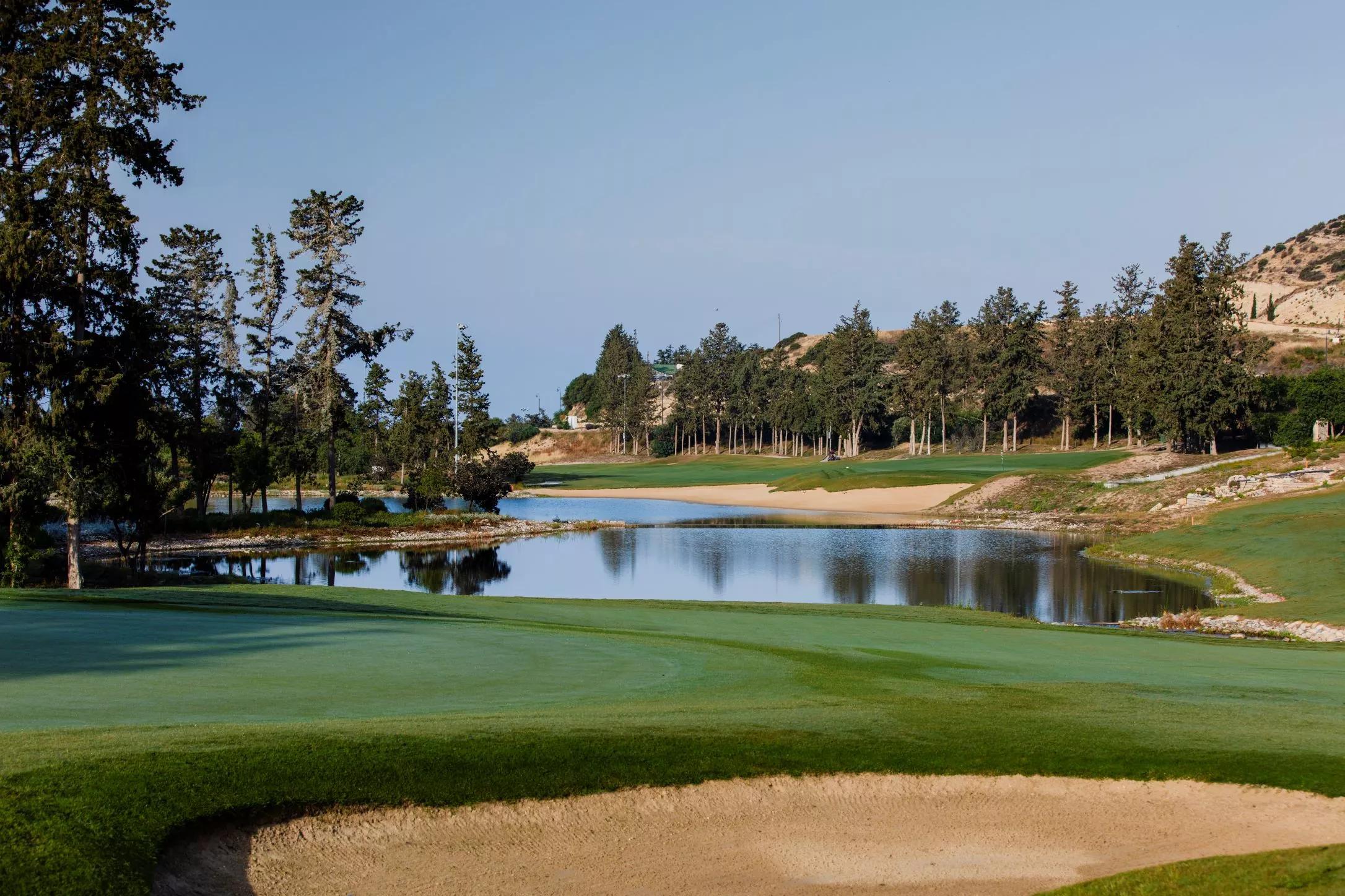 A calm pond reflecting trees and greens.
