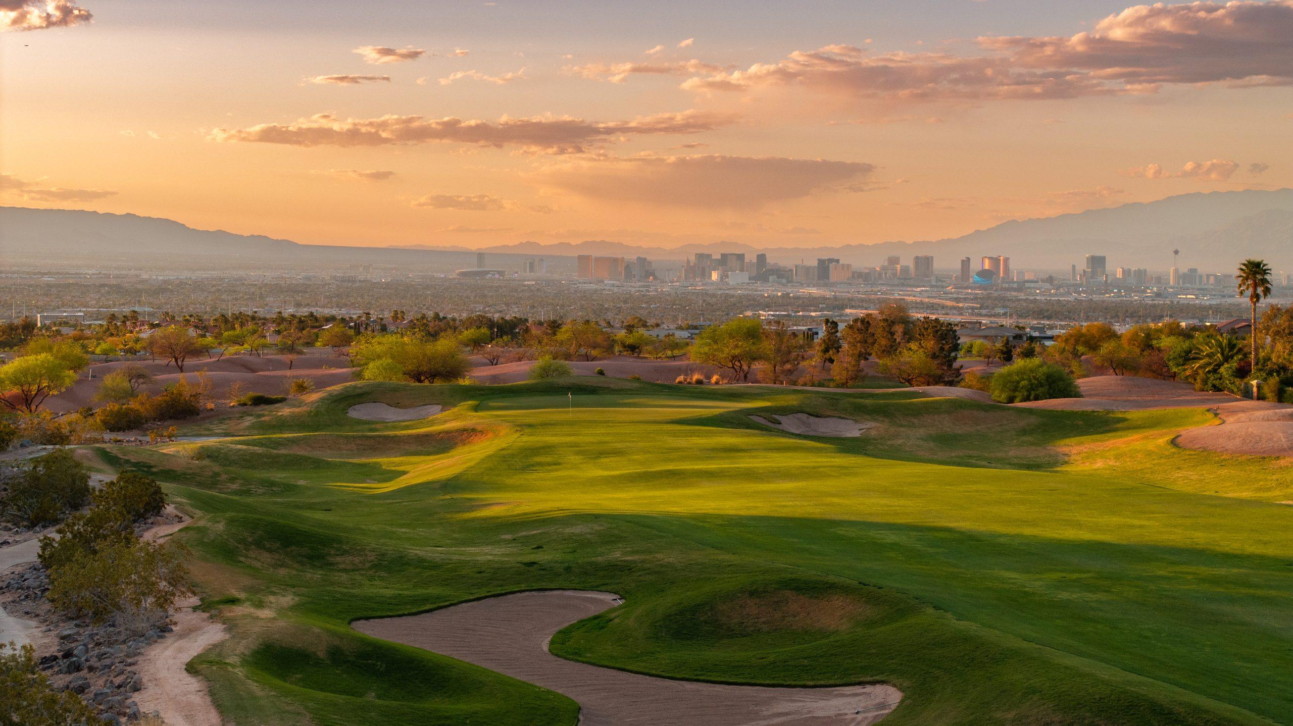 A sunset view over Serket Golf Club showcasing rolling greens and dramatic desert landscapes.
