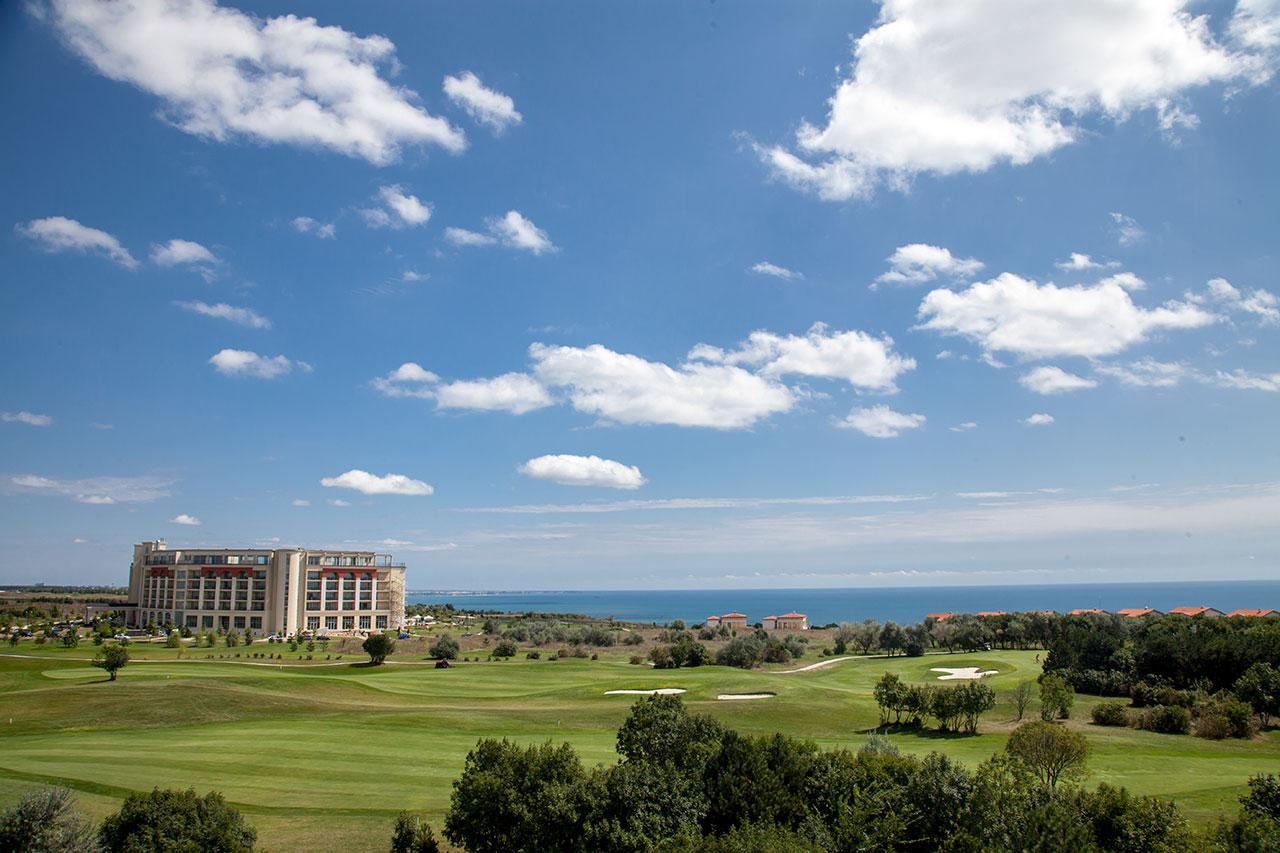 Coastal golf course with a hotel overlooking the sea.