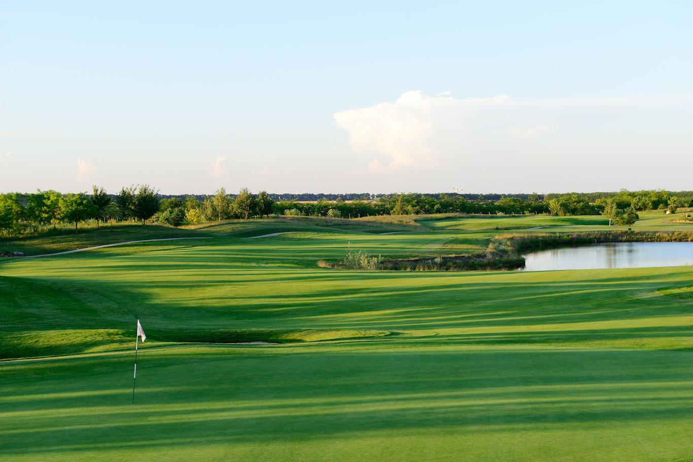 Lush green fairways with a water feature reflecting the clear sky.