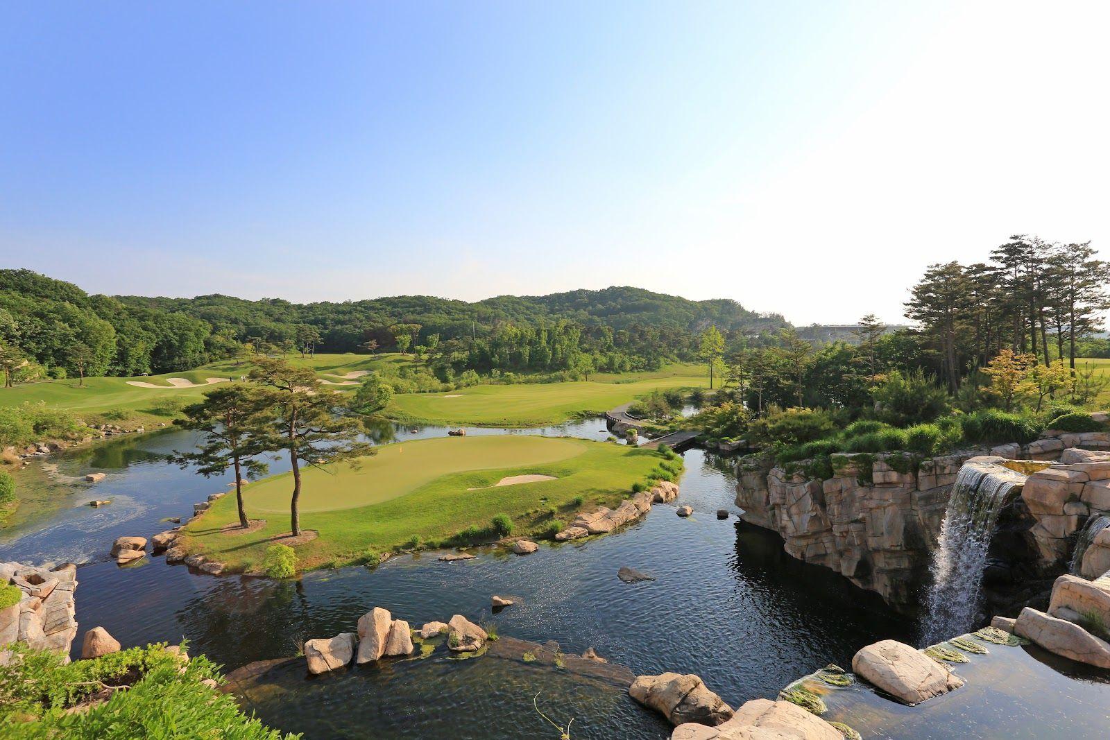 A smooth island green surrounded by water coming from a stone waterfall