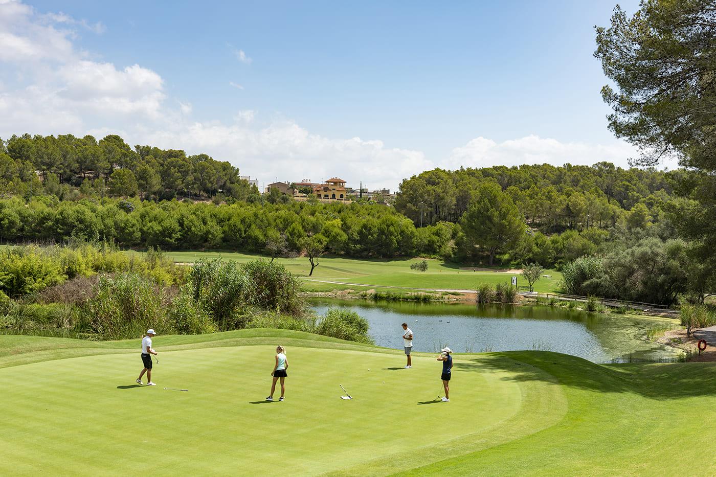 Four players on the green with a water hazard behind
