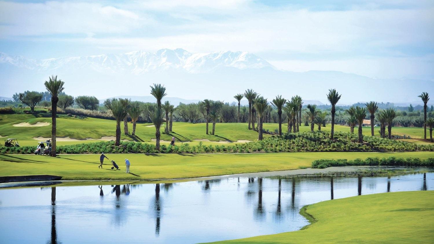 Golfers enjoying their round on a wide fairway sandwiched between palm trees and a water hazard