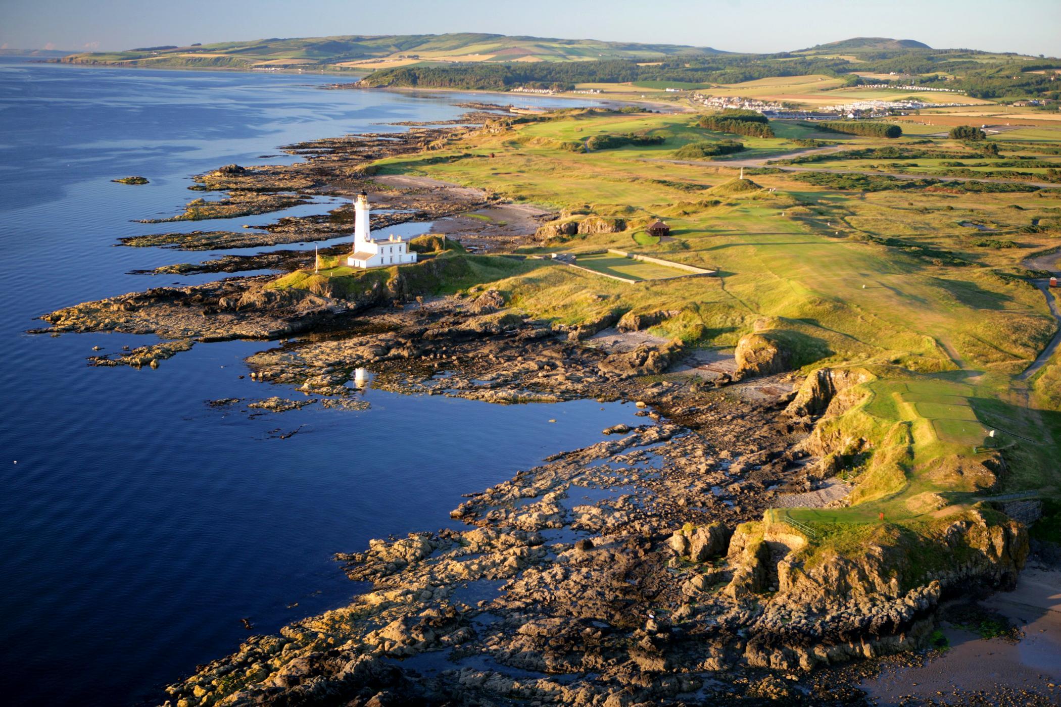 A stunning aerial view of a rugged coastline with a lighthouse at the edge of the golf course.