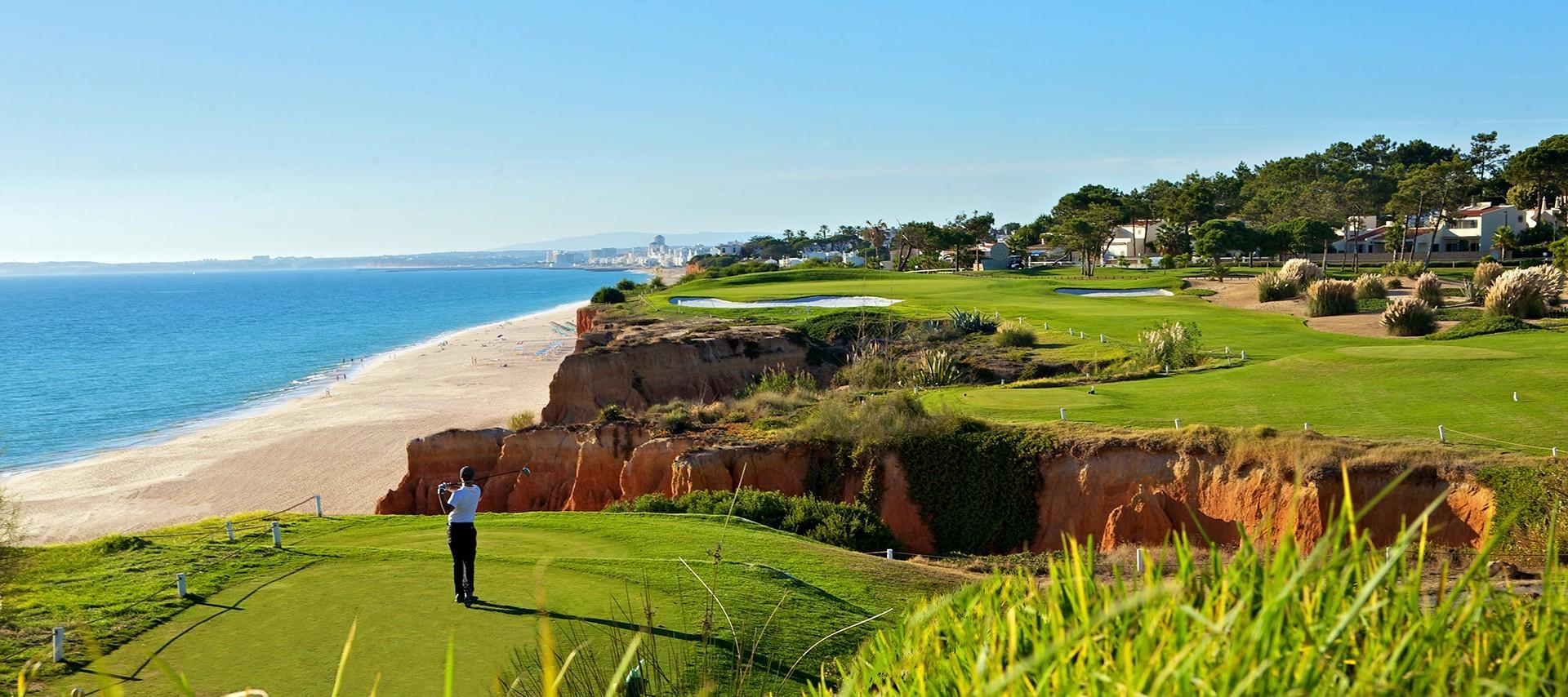 Player taking their tee shot on a long carry, cliffside Par 3 with the beach on the left