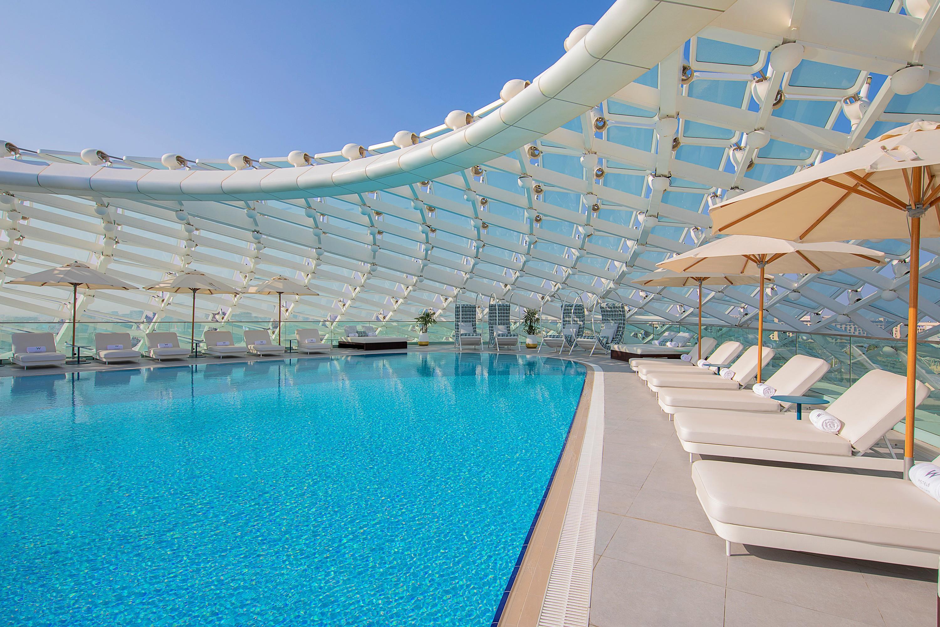 A roof top swimming pool at the resort surrounded by sunbeds and city views