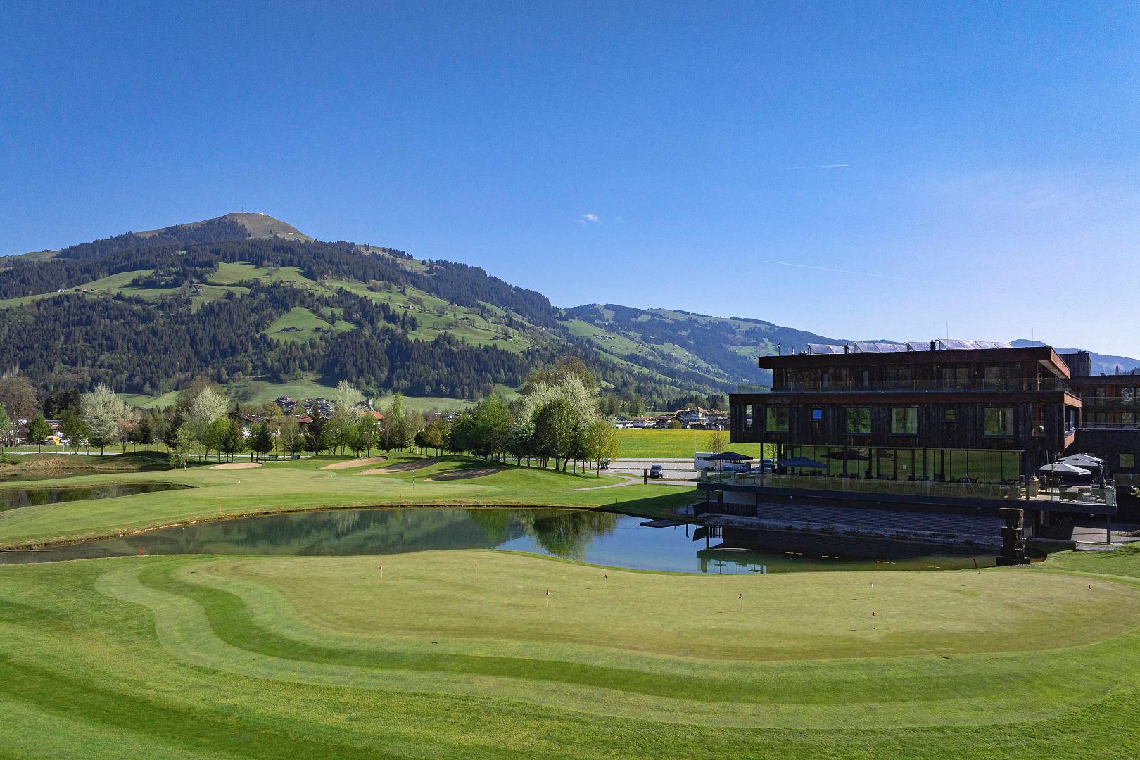A pristine golf course with a reflective pond next to the clubhouse.