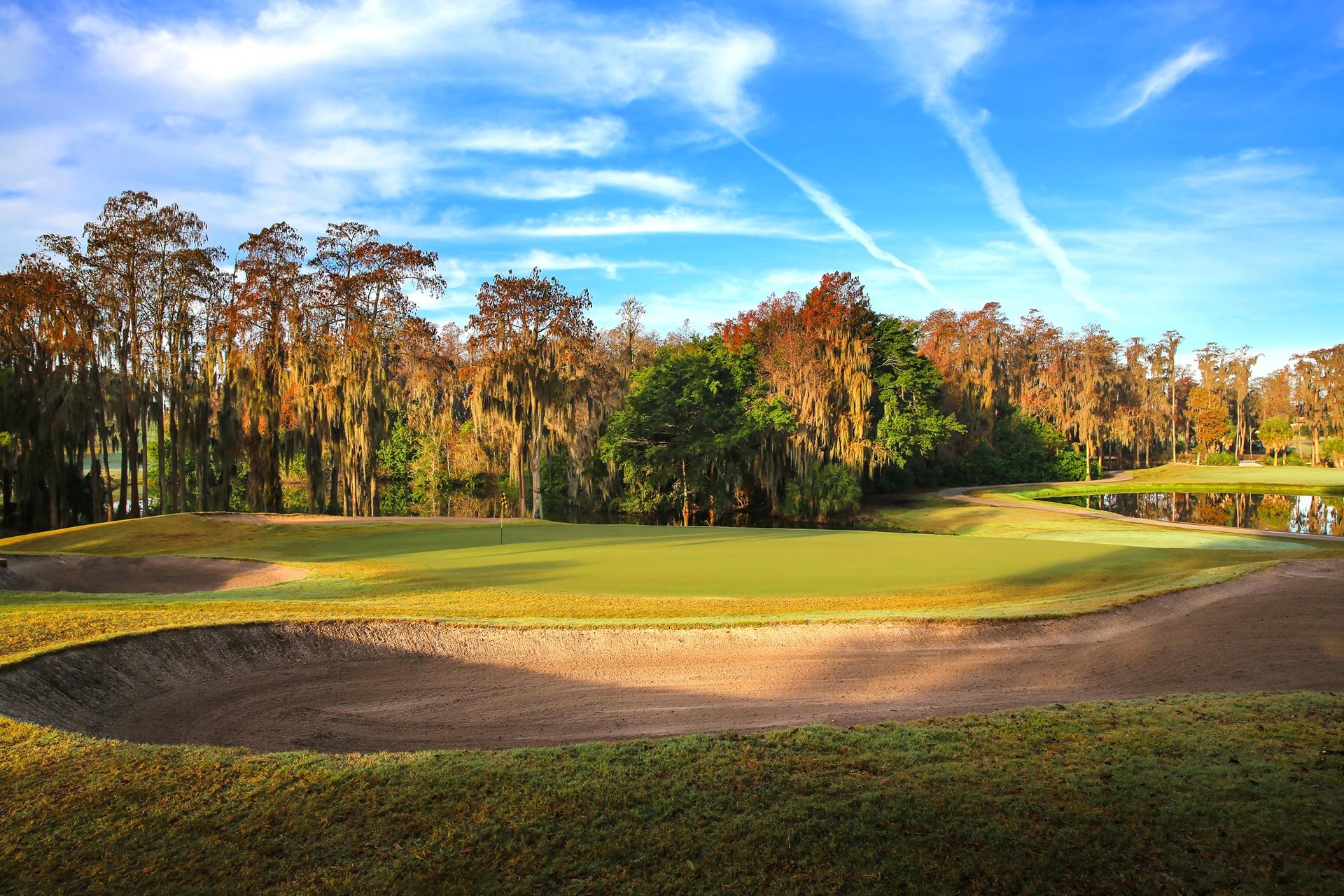 Large sand bunkers surrounding a smooth green under blue skies