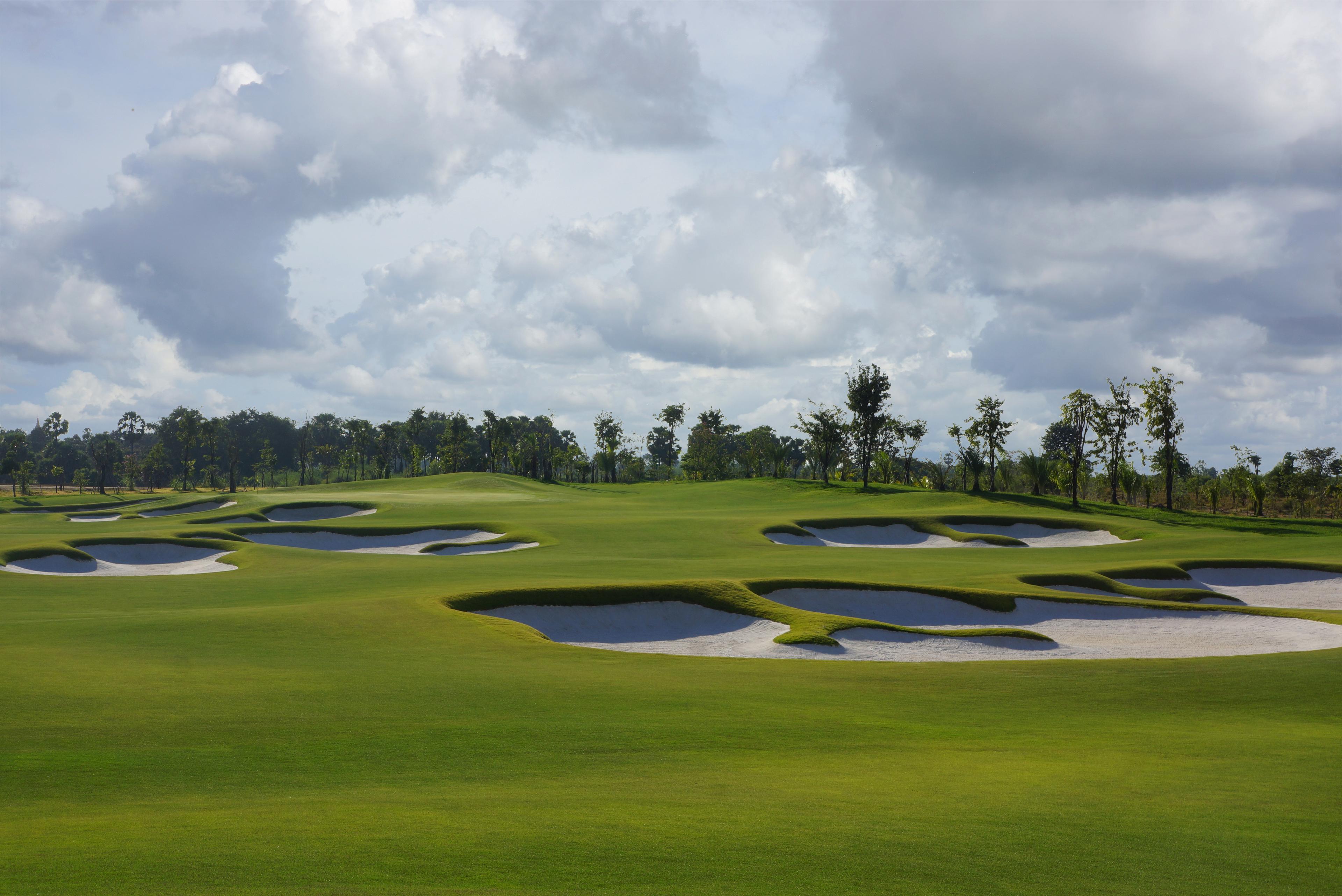 Panoramic view of a winding fairway littered with sand bunkers