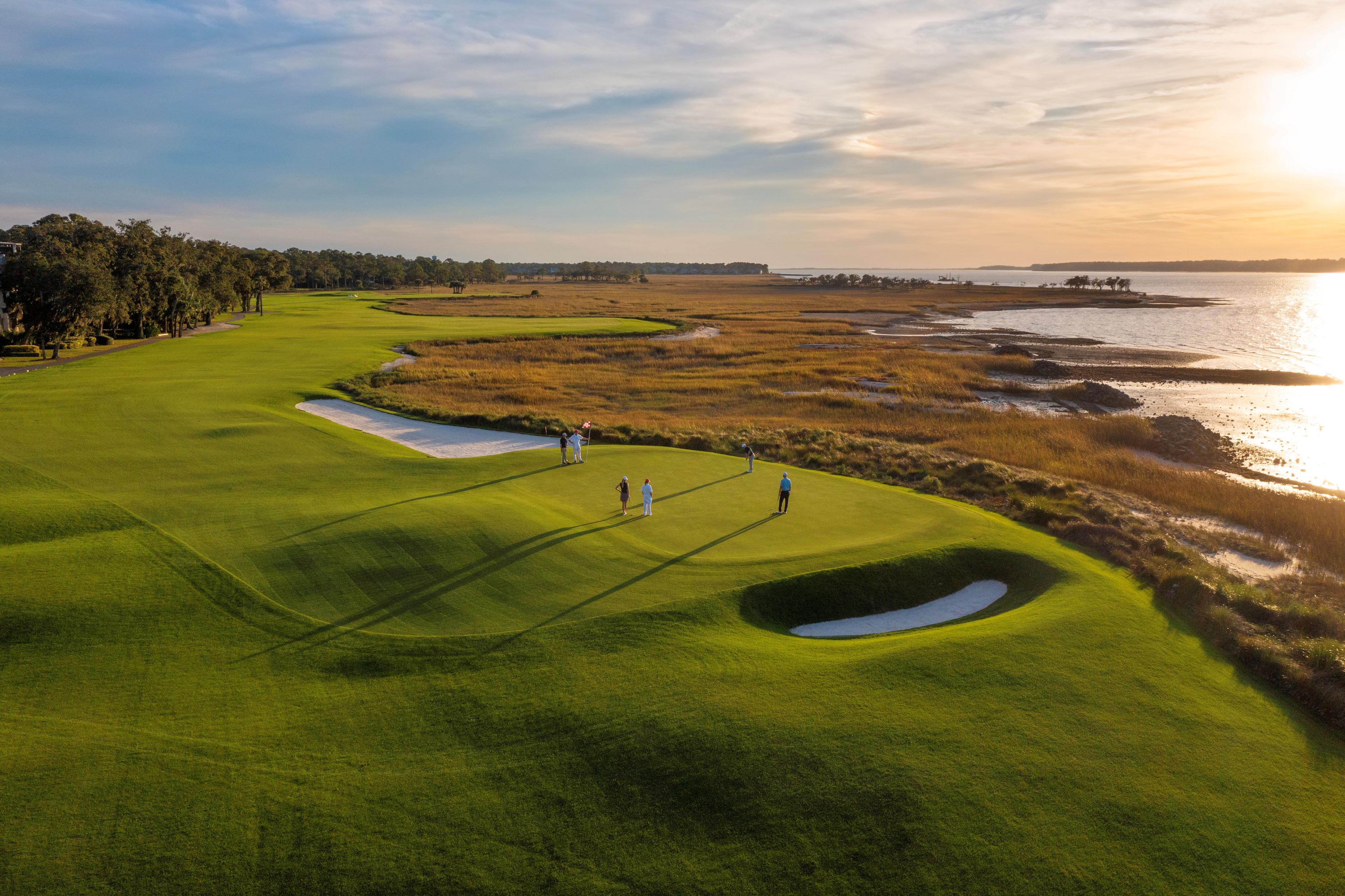 Overhead view of golfers enjoying their round on a manicured green with coastal views