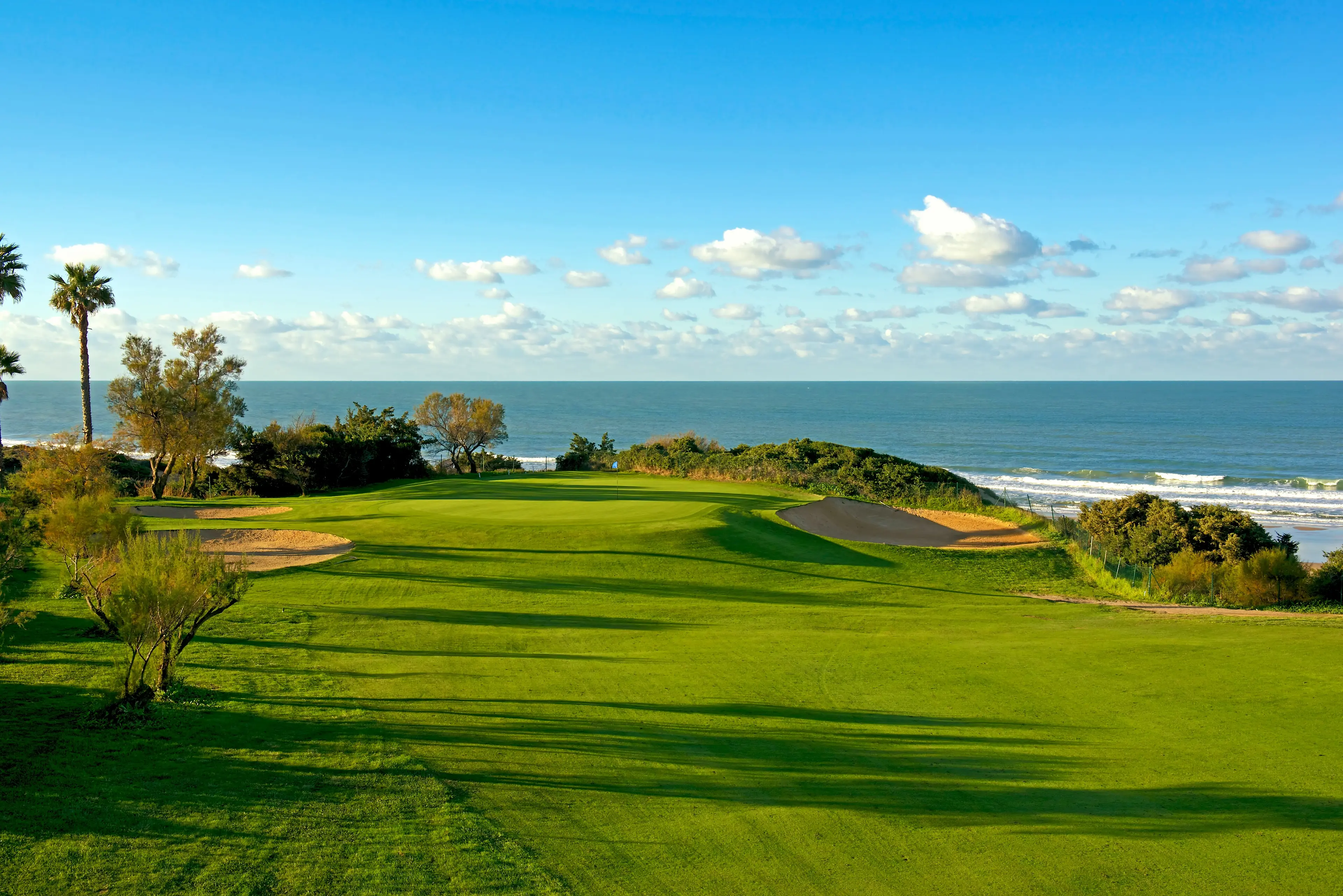 Panoramic view of a coastal green surrounded by sand bunkers