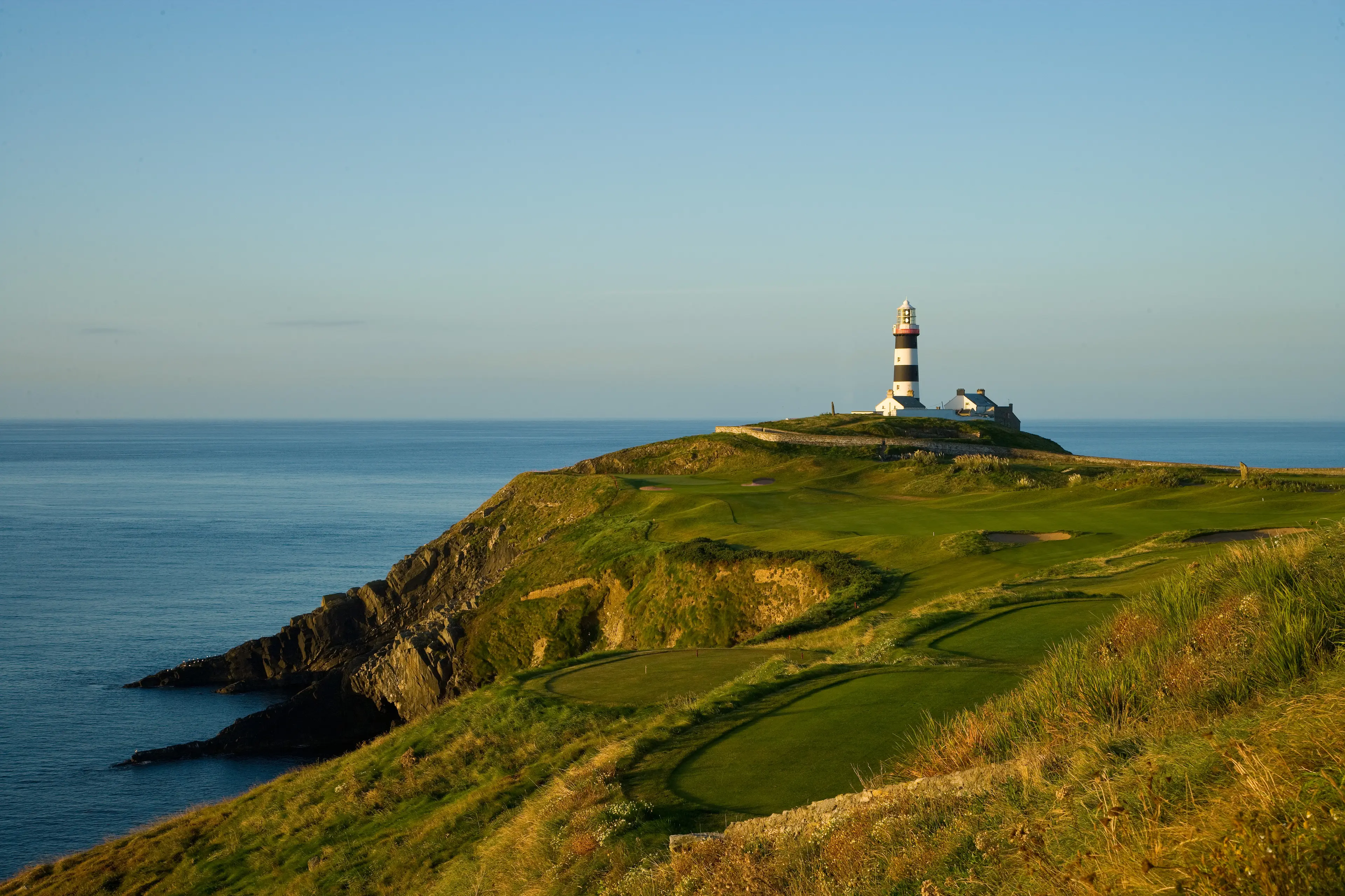 A well maintained coastal fairway with a lighthouse in the distance
